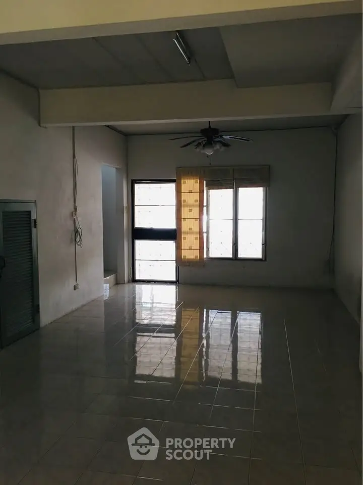 Spacious empty living room with tiled floor and ceiling fan, ready for customization.