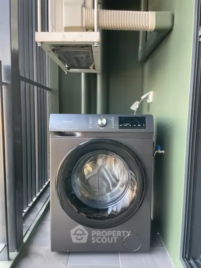 Modern washing machine on a small balcony with green walls and railing.