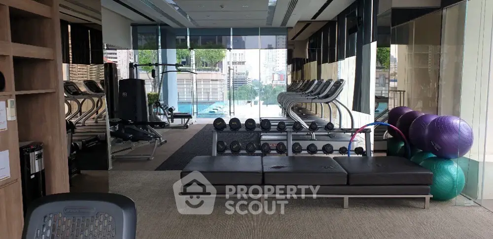 Luxurious gym with modern equipment and pool view in upscale residential building.