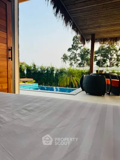 Luxurious poolside view from a modern patio with stylish outdoor furniture and lush greenery.