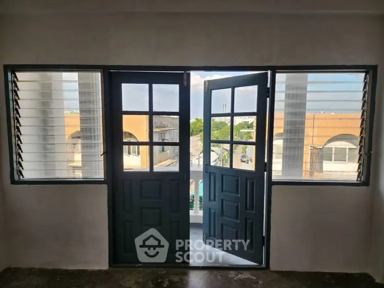 Charming balcony view with classic double doors and urban scenery.