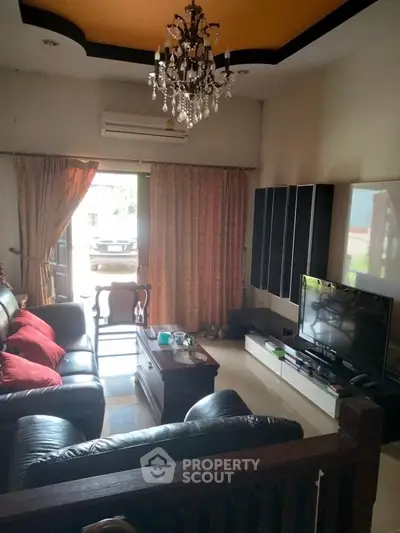 Cozy living room with elegant chandelier and modern entertainment setup.