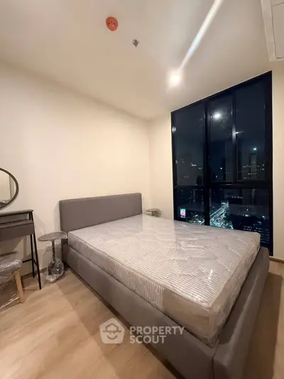 Modern bedroom with city view, featuring a stylish bed and elegant decor.