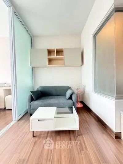 Modern living room with sleek furniture and wooden flooring in a bright apartment.