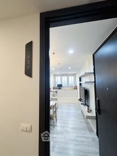 Modern apartment entrance leading to a stylish living room with sleek flooring and contemporary decor.