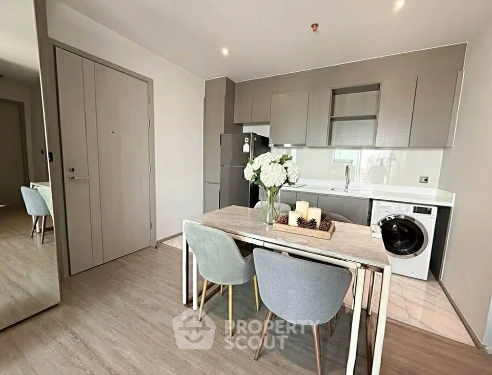 Modern kitchen with sleek cabinetry, dining table, and built-in washing machine in stylish apartment.