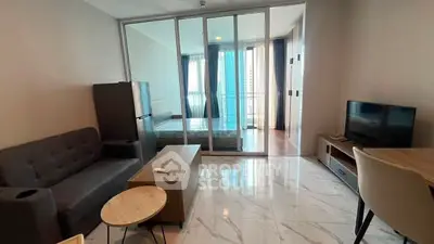 Modern living room with sleek furniture and glass partition leading to a bright bedroom with balcony view.