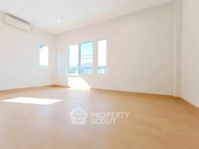 Spacious empty room with large windows and wooden flooring, perfect for customization.