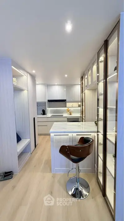 Modern kitchen with sleek cabinetry and stylish bar stool in a contemporary apartment.