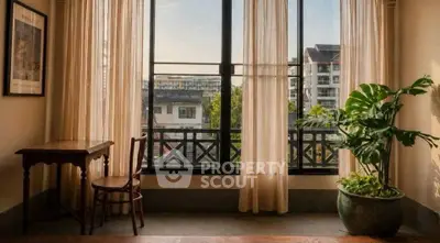 Charming interior with large window and city view, featuring elegant curtains and a cozy desk setup.