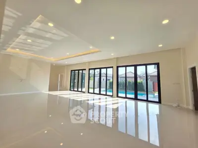 Spacious modern living room with large windows overlooking a pool and garden, perfect for luxury living.