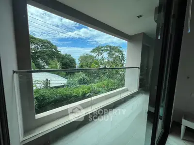 Modern balcony with glass railing offering lush green views and serene ambiance.