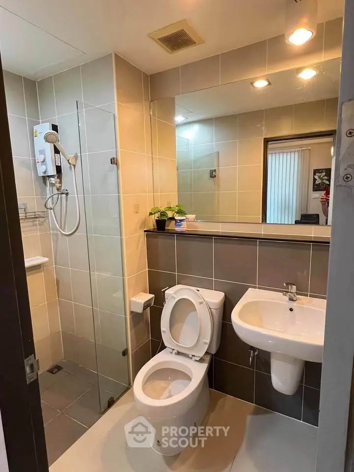 Modern bathroom with glass shower and sleek fixtures in contemporary apartment.