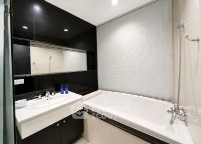 Modern bathroom with sleek black cabinetry and a spacious bathtub.