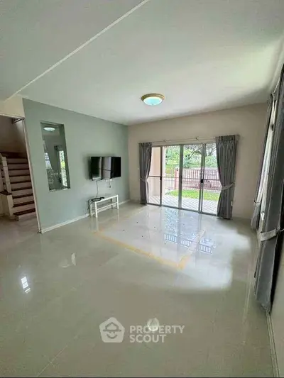 Spacious living room with large windows and garden view, ideal for family gatherings.