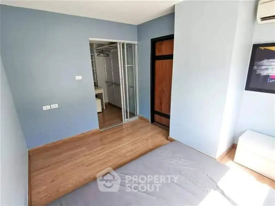 Spacious bedroom with wooden flooring and walk-in closet in modern apartment