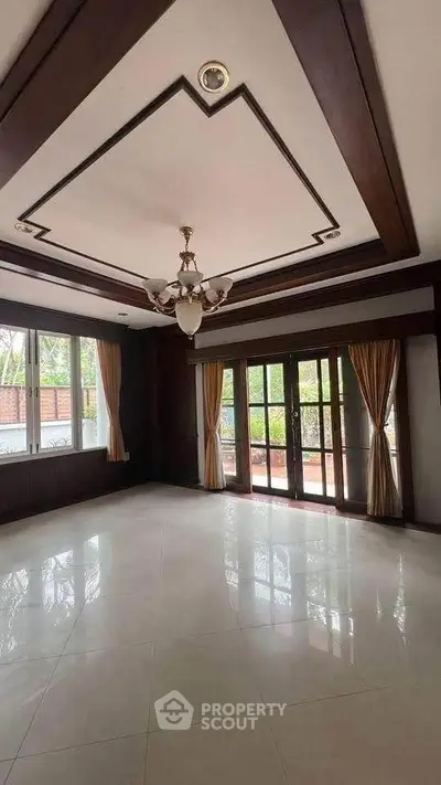Spacious living room with elegant chandelier and large windows offering natural light.