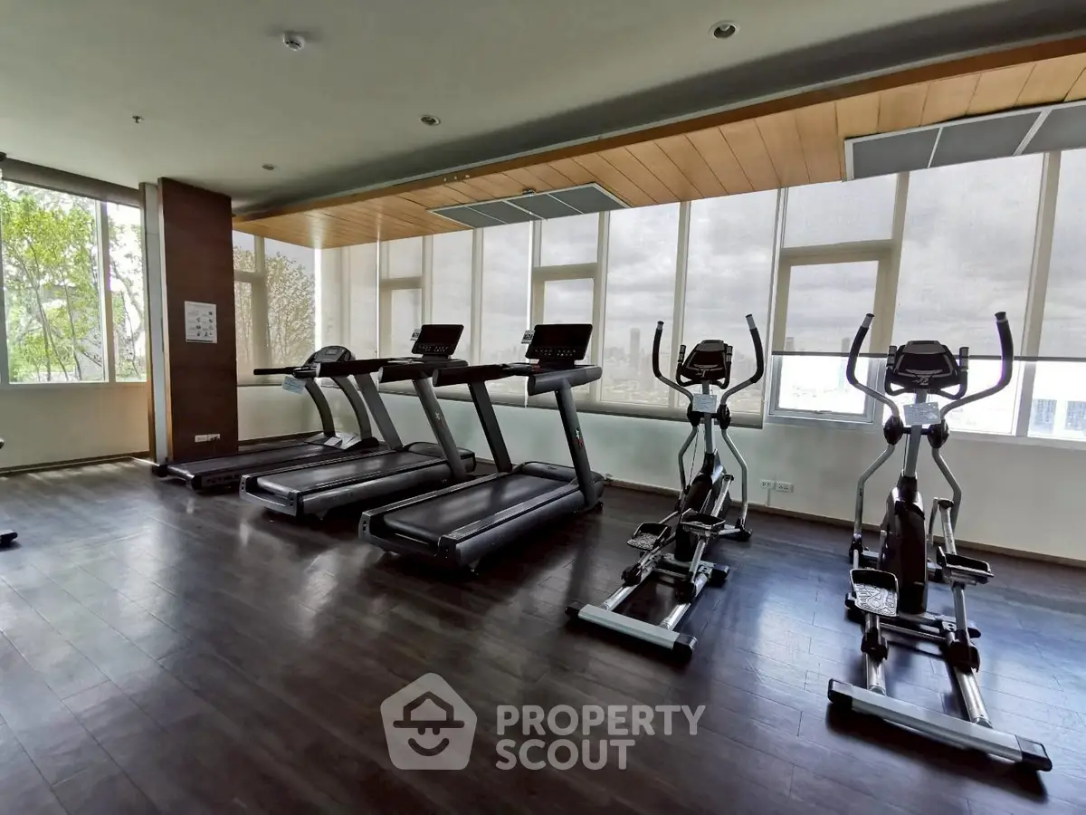 Spacious gym with modern treadmills and elliptical machines in a well-lit fitness center.