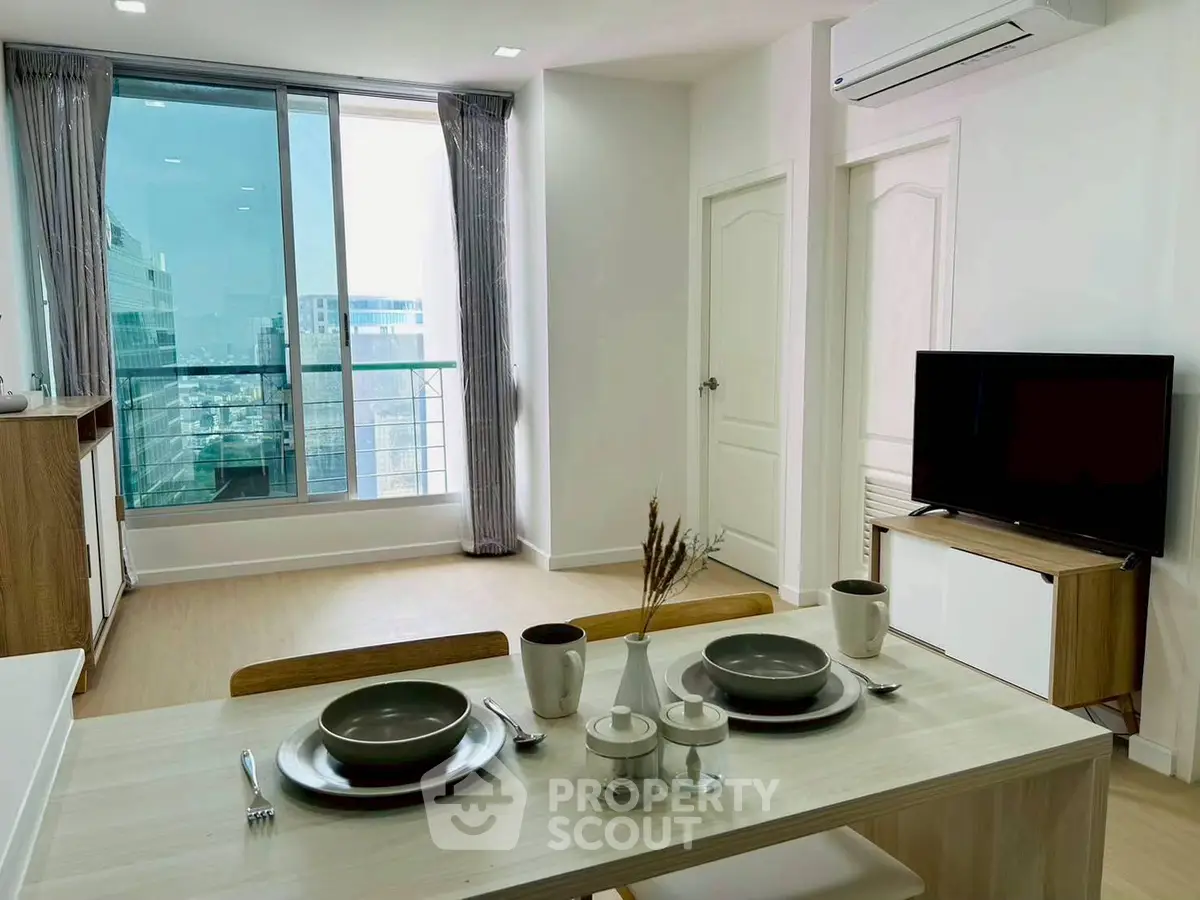 Modern living room with dining area and large windows offering city views.