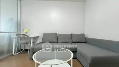 Modern living room with sleek gray sofa and glass coffee table, perfect for urban living.