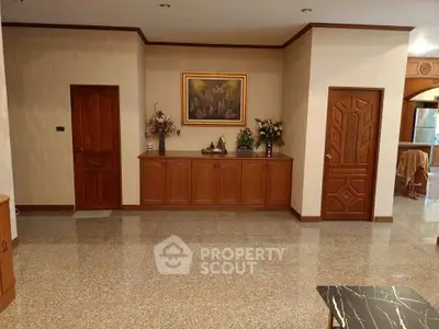 Spacious living room with elegant wooden cabinetry and polished stone flooring