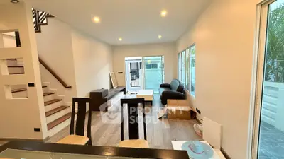 Spacious modern living room with open layout and stylish staircase, perfect for family gatherings.