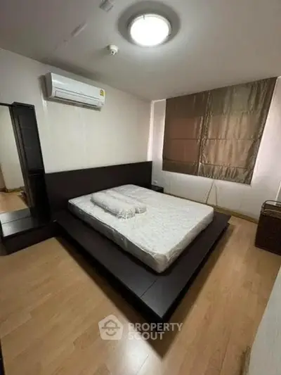 Spacious bedroom with modern platform bed and air conditioning in a stylish apartment.