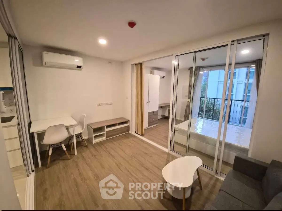 Modern studio apartment with open layout, featuring a cozy living area and a bedroom with balcony access.