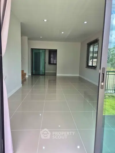 Spacious modern living room with large windows and glossy tiled floors, perfect for natural light and open living.