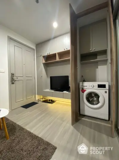 Modern apartment interior with washing machine and TV in compact living space.