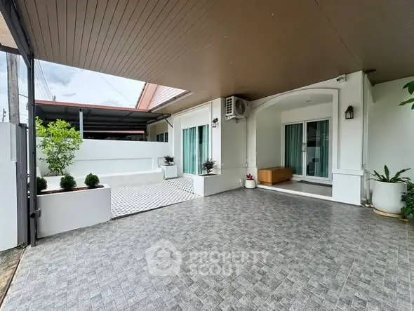 Spacious modern home exterior with covered patio and stylish tiled flooring.