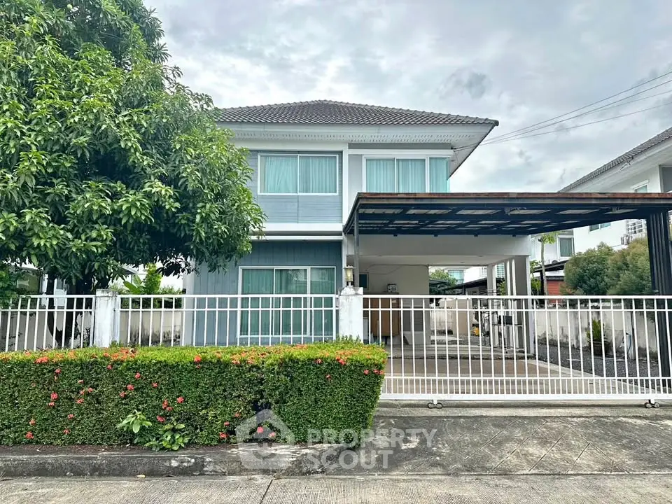 Charming two-story house with lush garden and gated driveway in a serene neighborhood.