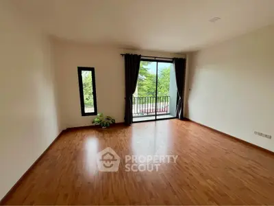 Spacious empty living room with wooden flooring and balcony view