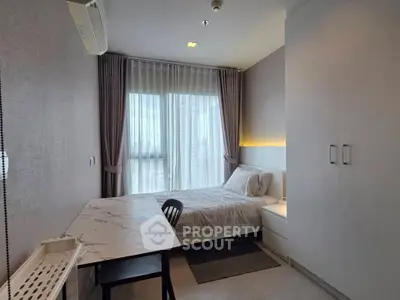 Modern bedroom with stylish decor and natural light, featuring a cozy bed and sleek furniture.