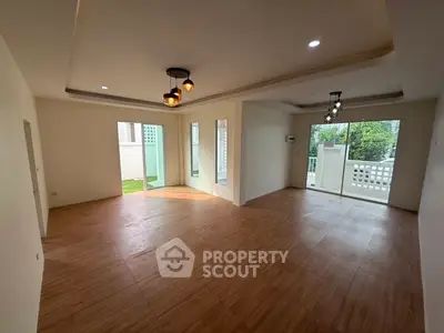 Spacious modern living room with wooden flooring and large windows offering garden views.