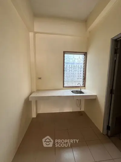 Minimalist kitchen space with tiled countertop and single sink, ideal for compact living.