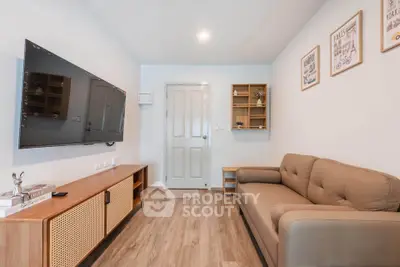 Cozy living room with modern decor, wall-mounted TV, and comfortable sofa in a stylish apartment.