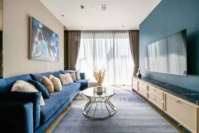 Luxurious modern living room with blue sofa, large TV, and elegant decor