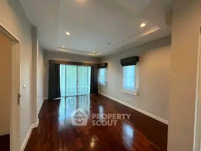 Spacious living room with polished wooden floors and large windows for natural light.