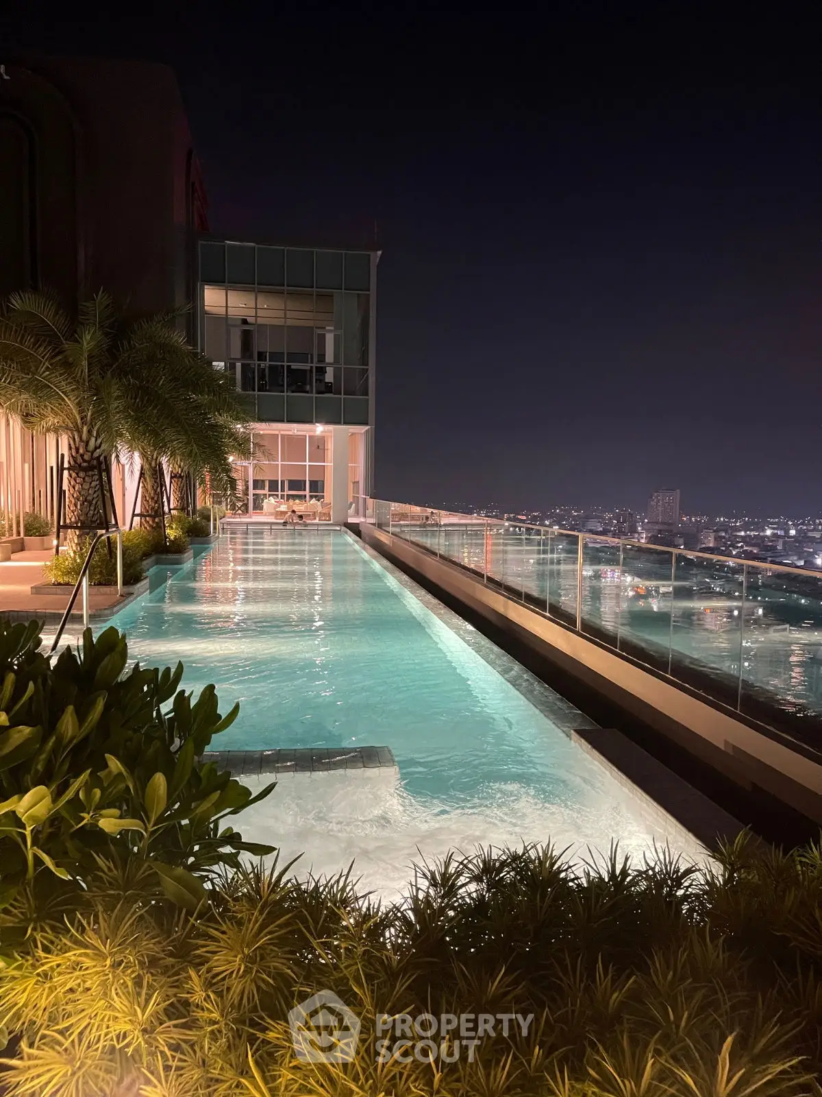 Luxurious rooftop pool with stunning city skyline view at night.