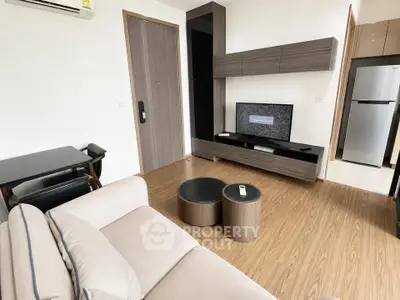 Modern living room with sleek furniture and wooden flooring, featuring a TV and air conditioning.