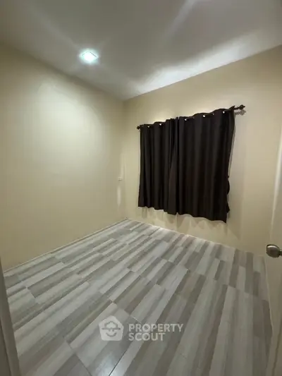 Spacious empty room with tiled flooring and dark curtains, perfect for customization.