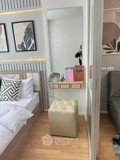 Modern bedroom with stylish decor, featuring a cozy bed, wall art, and a chic mirror with a small shelf.
