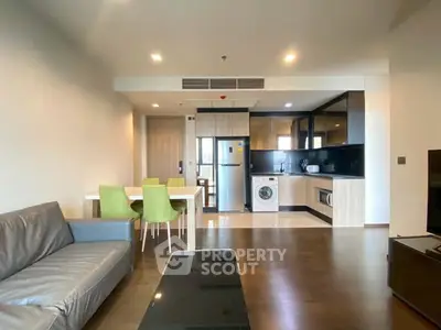 Modern open-plan living room with kitchen, dining area, and appliances in a stylish apartment.