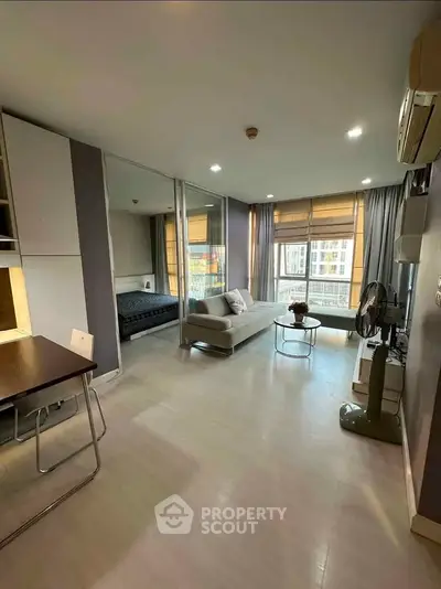 Modern studio apartment with open layout and large windows offering city views.