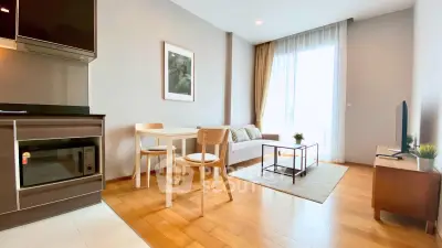 Modern living room with open kitchen, wooden flooring, and natural light.