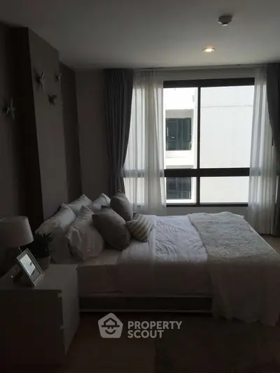 Cozy bedroom with large window and modern decor in a stylish apartment.