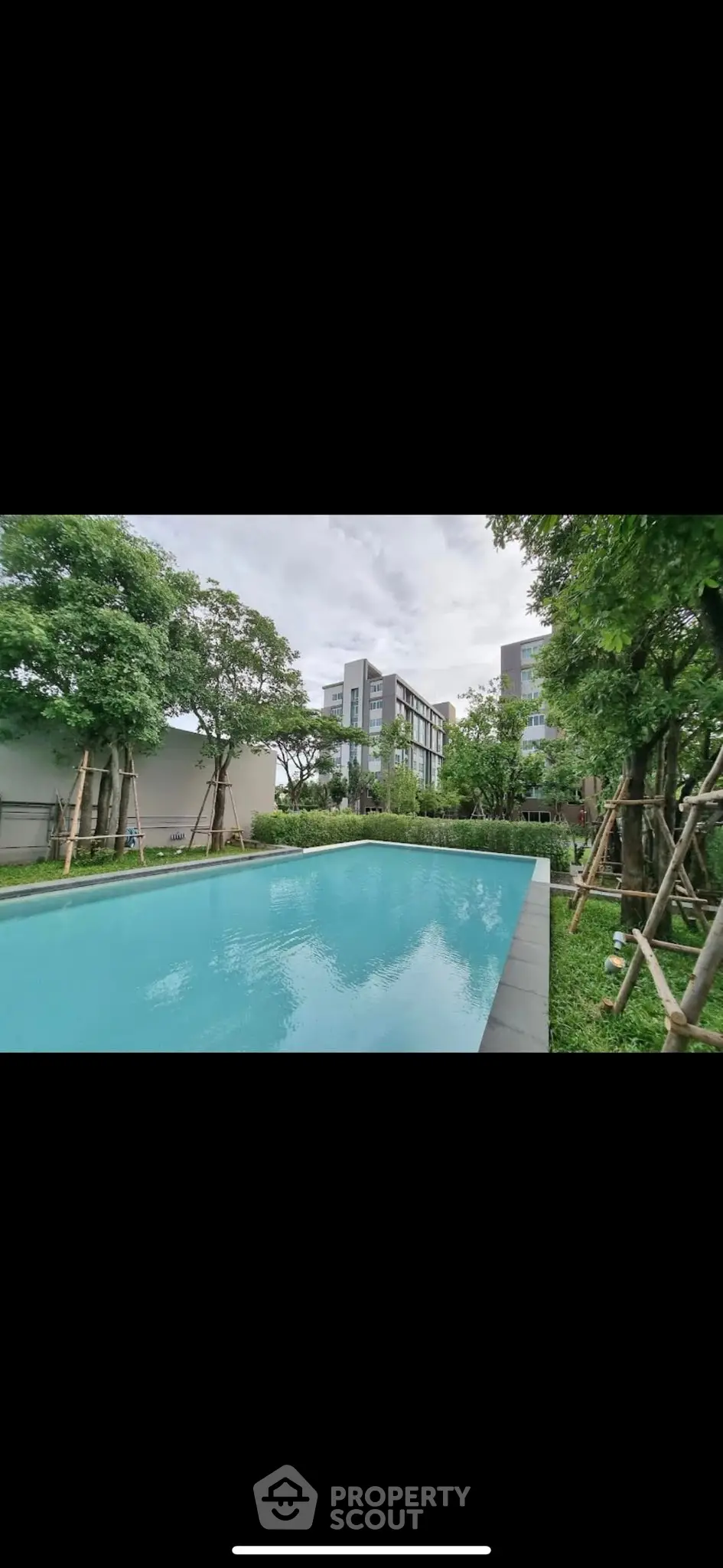 Luxurious residential pool with lush greenery and modern architecture.