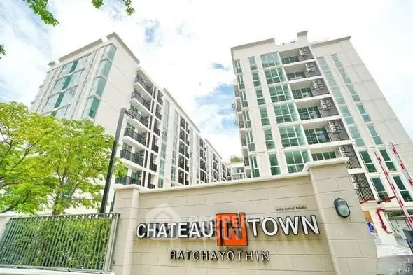 Modern condominium building exterior with lush greenery and clear blue sky.