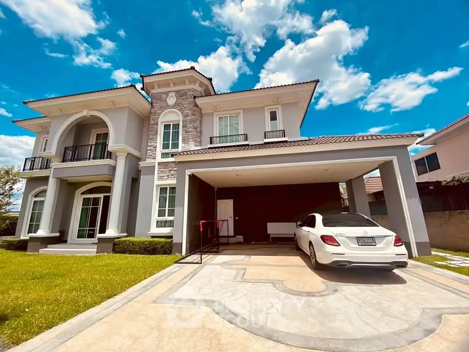 Luxurious two-story house with elegant facade and spacious driveway under a clear blue sky.